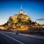 Sunset at Mont Saint Michel. Man sitting on sidewalk