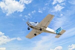 a small plane that is flying in the sky over some grass