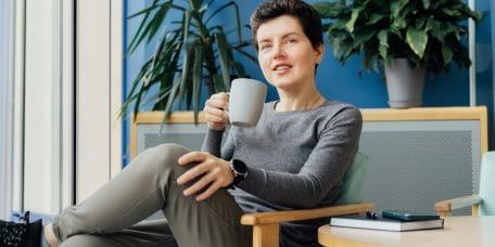 Smiling Neutral gender middle aged business woman in casual clothing relaxing with coffee cup