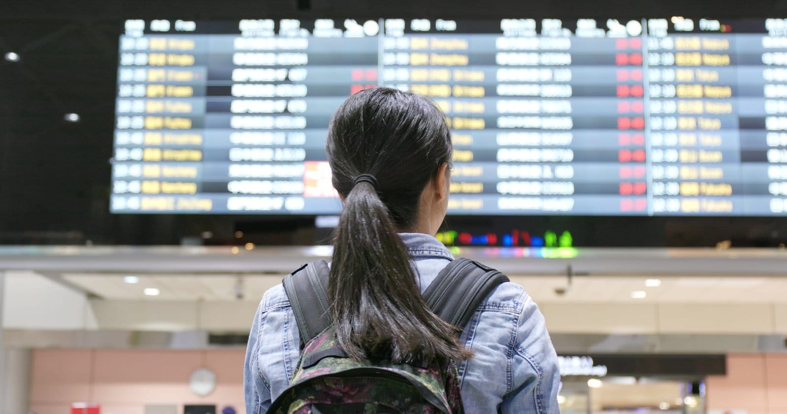 Young woman traveler looking for the flight number number at airport