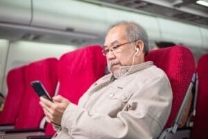 Asian senior man playing mobile phone on airplane