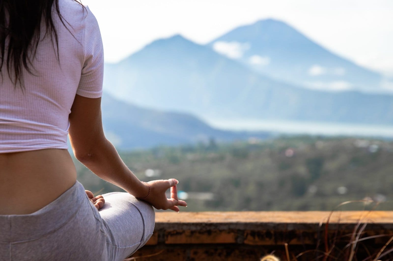Beautiful sporty woman is doing morning yoga with montains and volcano view on sunrise