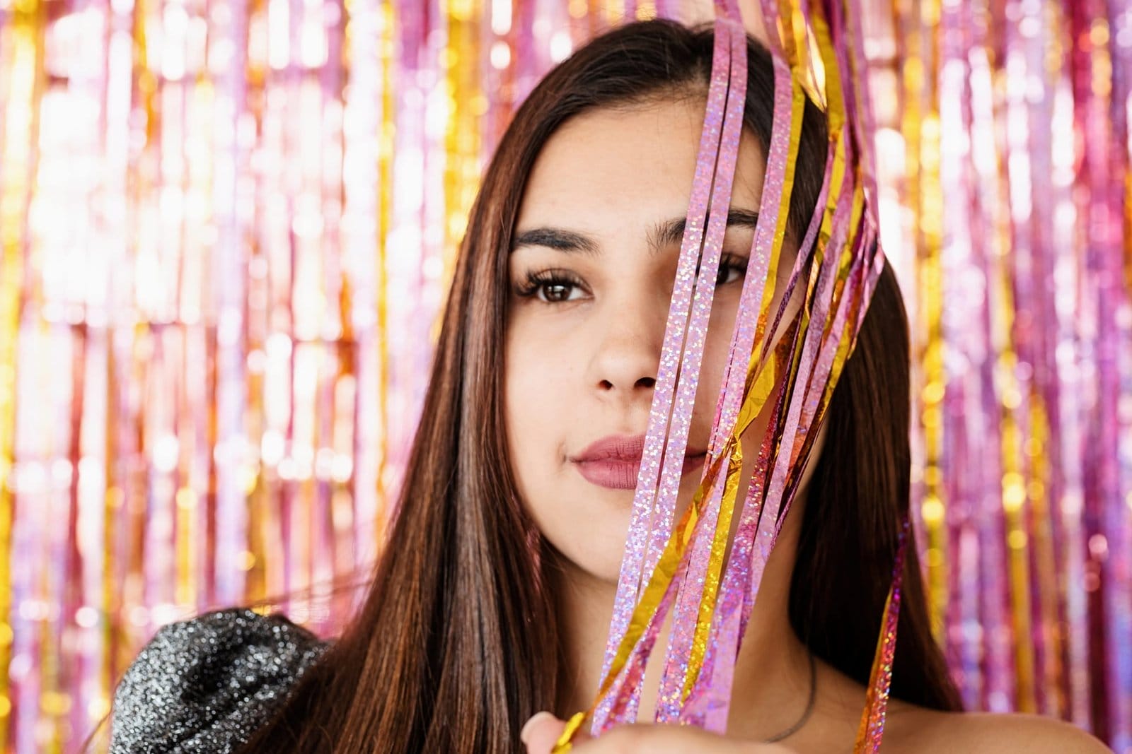 Closeup of woman in glitter dress standing on glitter purple and gold background