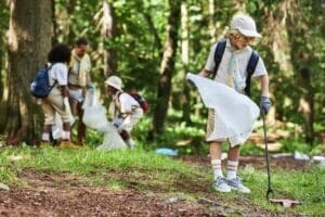 Cute boy as scout helping clean forest during eco awareness field trip
