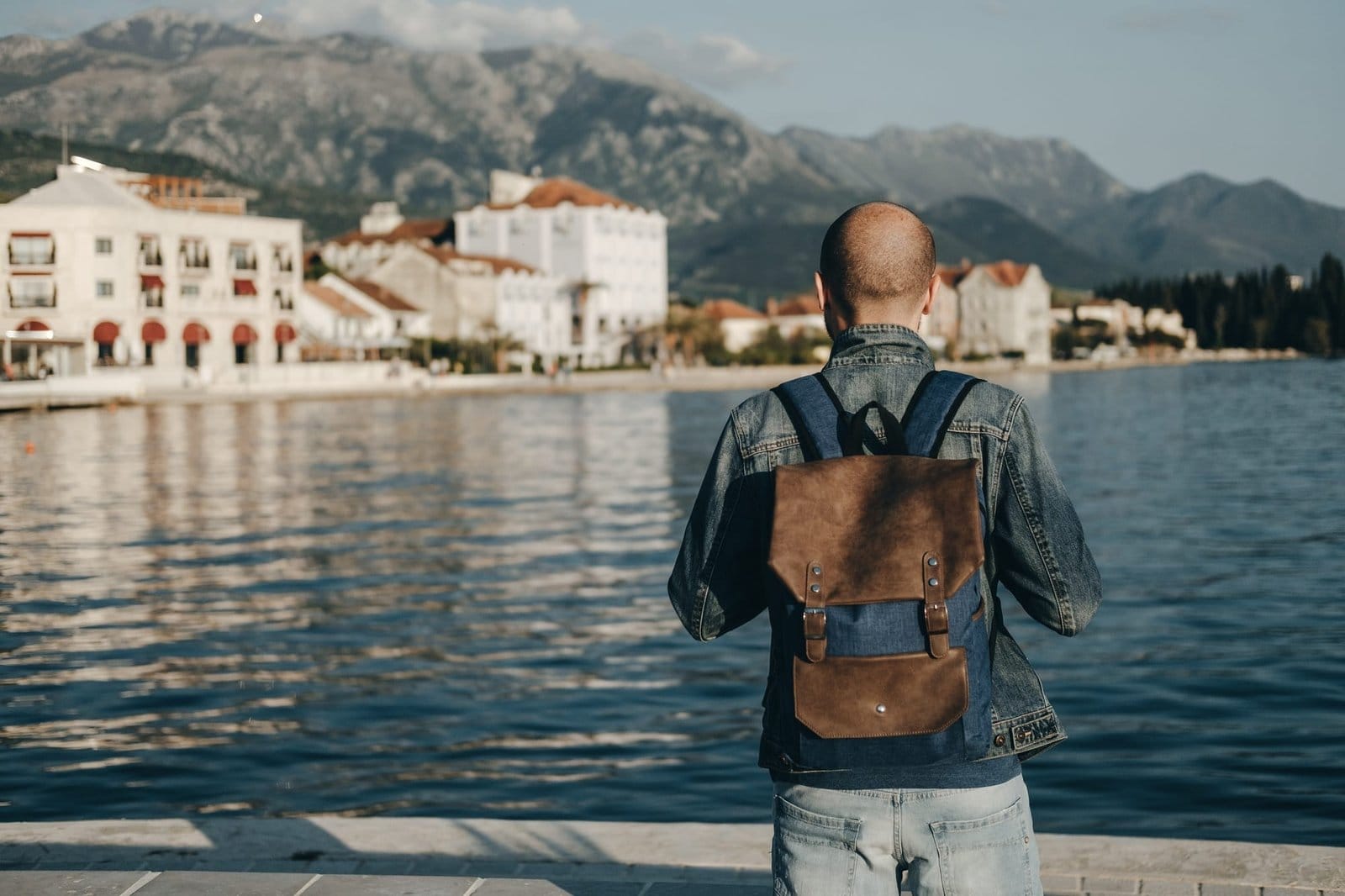 Young traveler man with backpack staying alone looking to the sea.