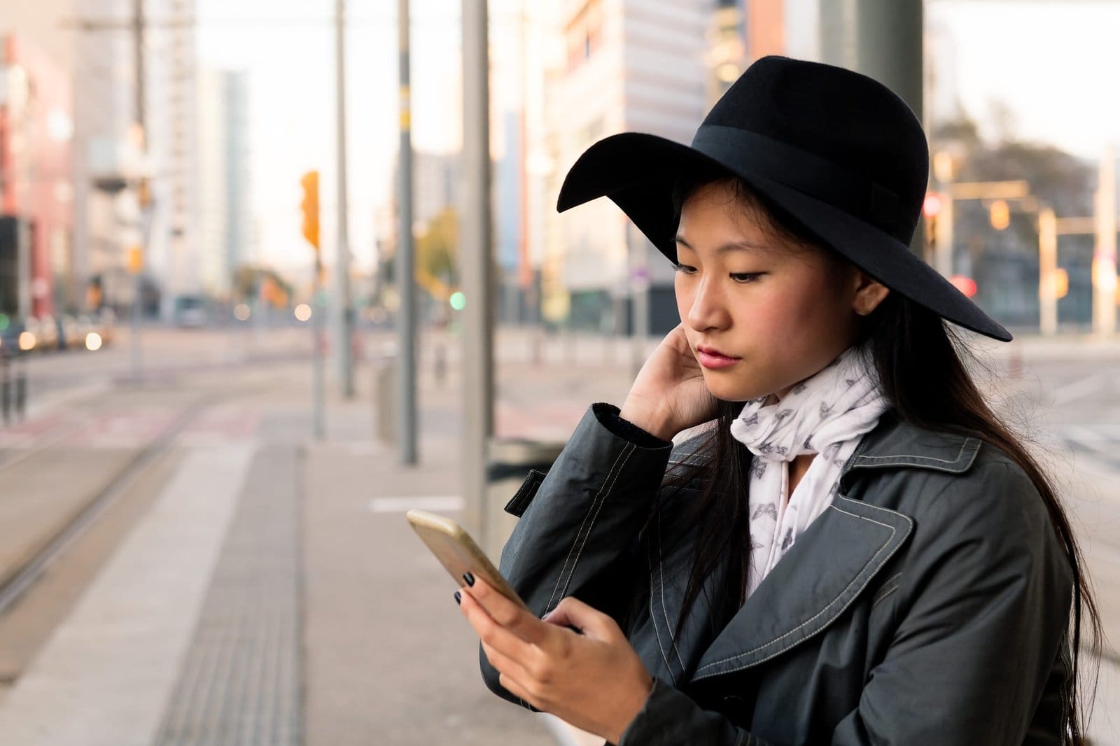 young woman consulting cell phone waiting the tram