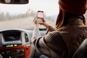 girl in a car with a phone in her hands outdoors