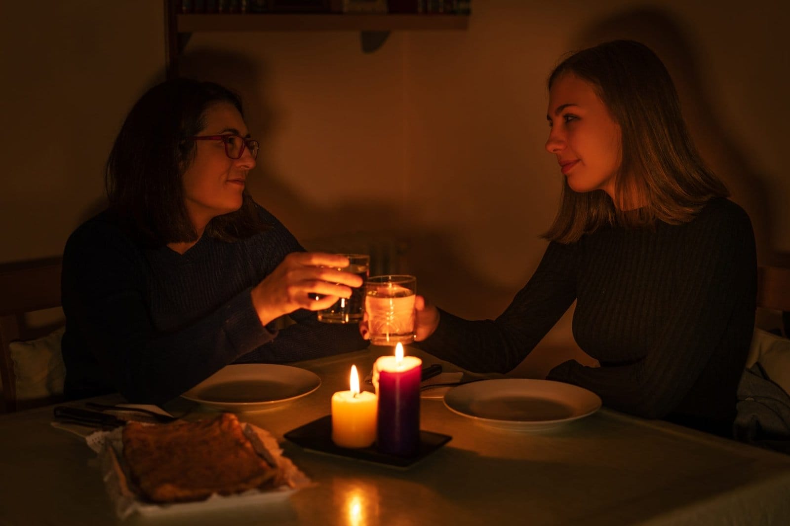 One-parent family dining by candlelight. Blackout concept, power cut