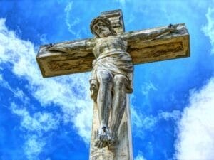 Statue of Jesus on cross against blue sky