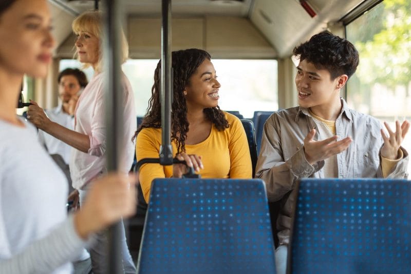 Happy young multiciltural friends taking bus together