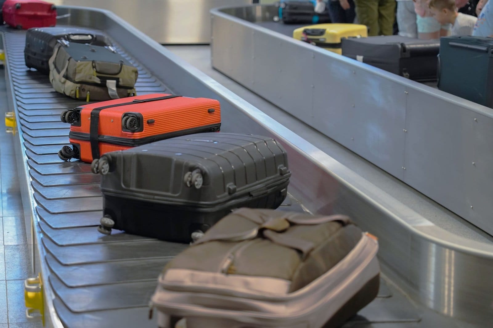 Suitcases on a baggage carousel at an airport with waiting guests in the background Suitcases on a baggage carousel at an airport with waiting guests in the background