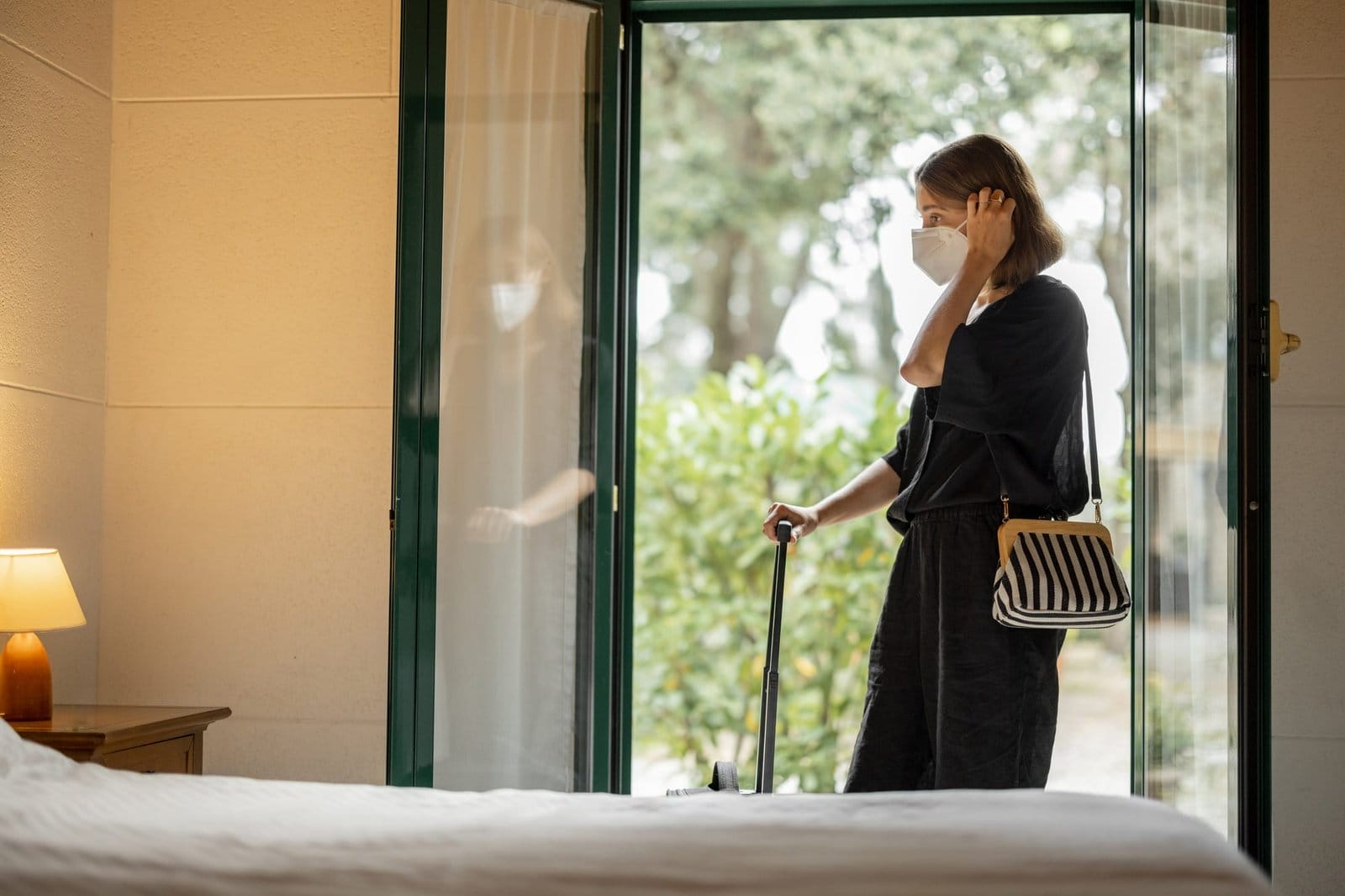 Woman in medical mask entering in hotel room