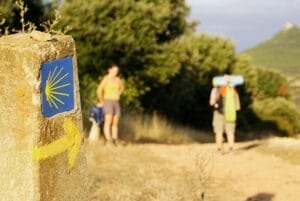 Woman hiker rests next to a sign of the Camino de Santiago in Spain during her adventure